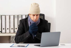 Worker bundled up in front of their computer on a cold day in the office